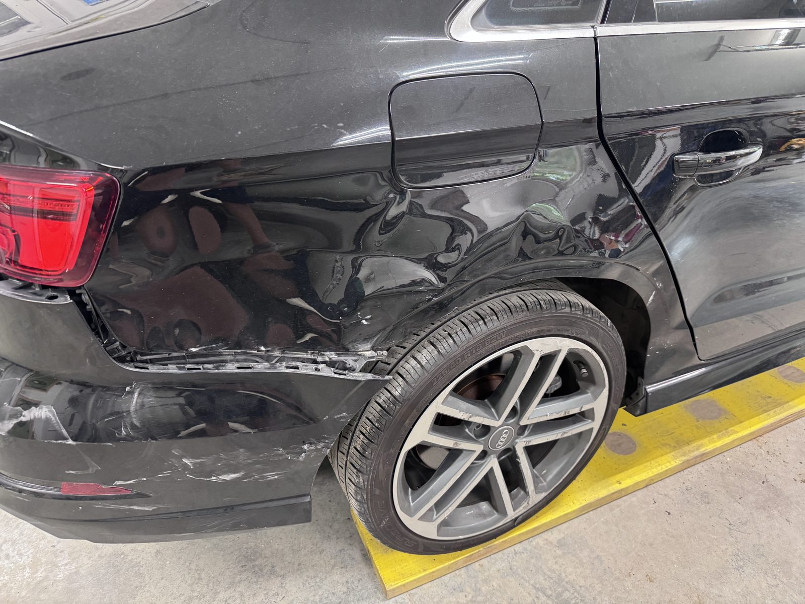 Collision damage around the rear quarter panel of a black Audi