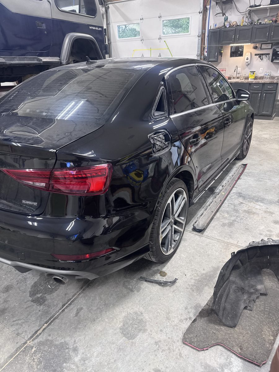 Refinished rear quarter area of black Audi with a small trim piece still removed