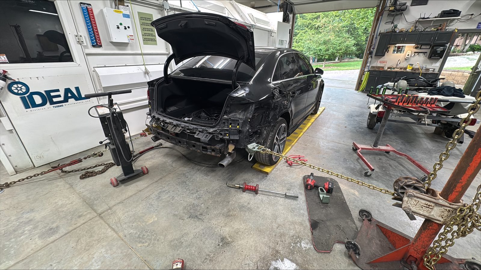 Black Audi with rear bumper and trim removed during teardown
